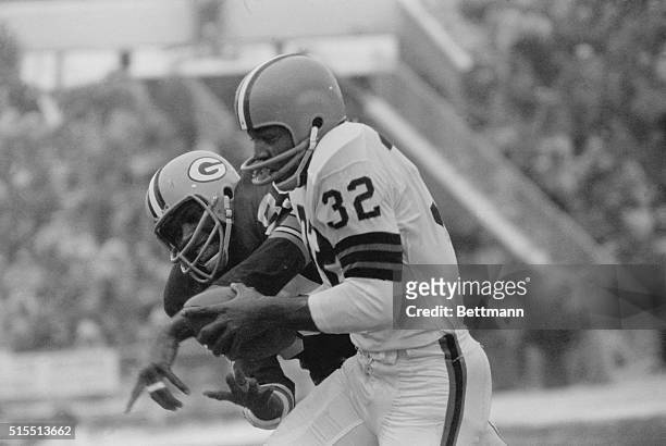 Jim Brown, fullback of Browns, holds ball in hands as Packers defender Dave Robinson takes a swat at it in first period of NFL title game. Brown has...