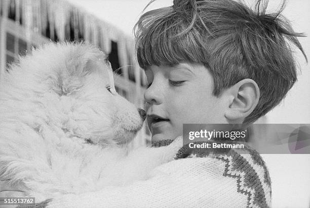 John F. Kennedy Jr. Nuzzles up to a Samoyed pup from the sled dog concession here, December 30, 1965. John Jr., who is vacationing here with his...