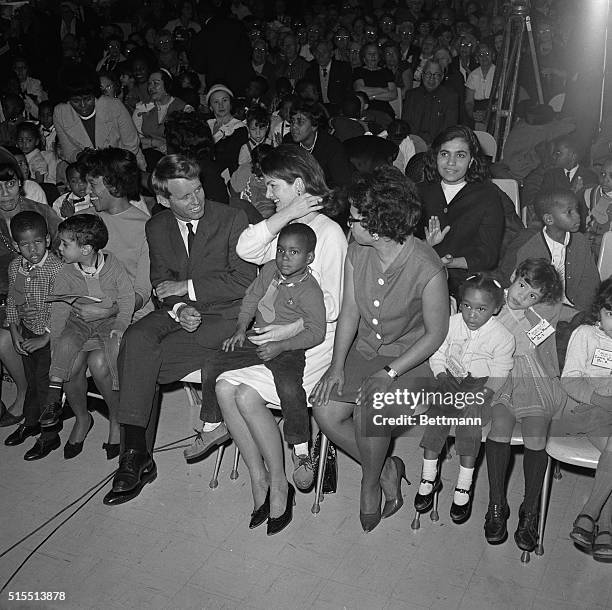 Senator Robert F. Kennedy, NY, talks to Mrs. Jacqueline Kennedy, who holds four-year-old Bobby Johnson, who lives at the Claremont Housing Project...