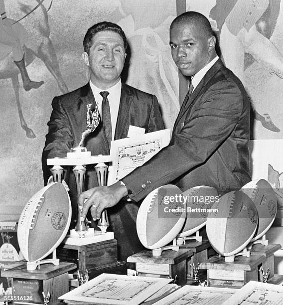 S Murray Olderman and Rookie of the Year, Chicago Bears' Halfback, Gale Sayers, admire certificates, auto graphed footballs and Sayers' trophy at the...