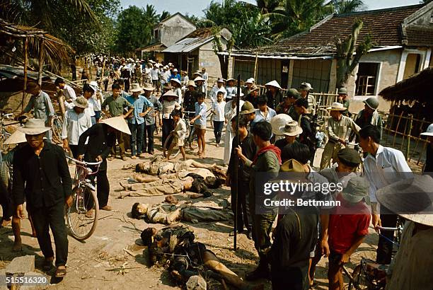 Ngong Giang villagers view Viet Cong bodies laid on the village road by South Vitnamese Infantrymen, March 28. The Viet COng were killed when their...