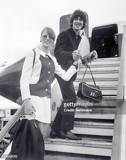 Beatle George Harrison and his wife, former model Patti Boyd, walk to their plane at London Airport February 8th at the start of a delayed honeymoon...
