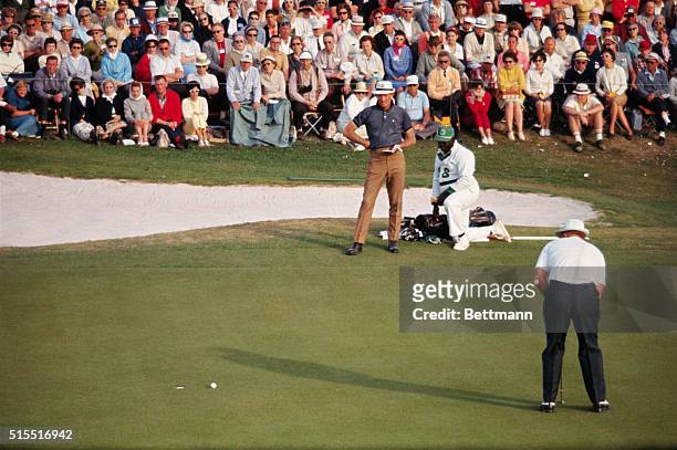Jack Nicklaus putts out on 18th hole as Don January looks on. Nicklaus finished this third round of play in the Masters Golf Tournament, in a first...