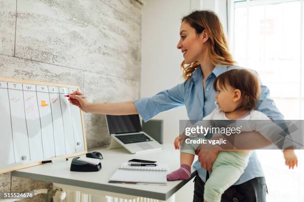 mãe trabalhando de casa e segurando seu bebê - working mother - fotografias e filmes do acervo