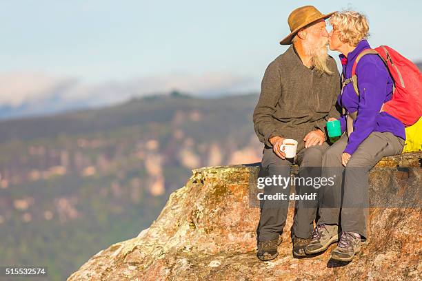 senior couple kissing while taking a break from bushwalking - outback stock pictures, royalty-free photos & images
