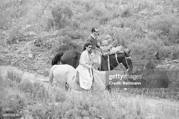 Wearing the traditional pants of Argentine gaucho, Mrs. John F. Kennedy rides through the mountains of Cordoba accompanied by Dr. Jose A,. Martinez...