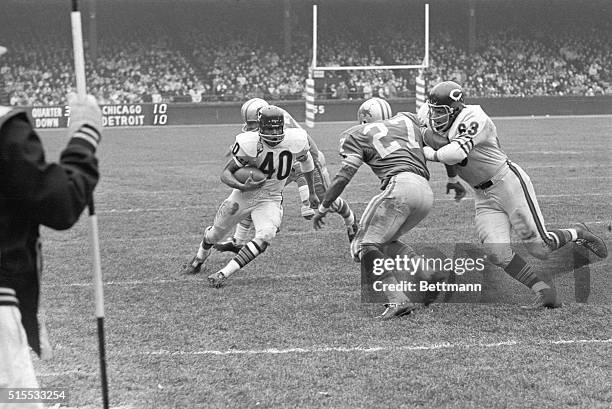 With an assist from tackle Bob Wetoska , Bear halfback Gale Sayers eludes Lion defensive back Bobby Thompson as he runs 20-yards for a Bear touchdown...