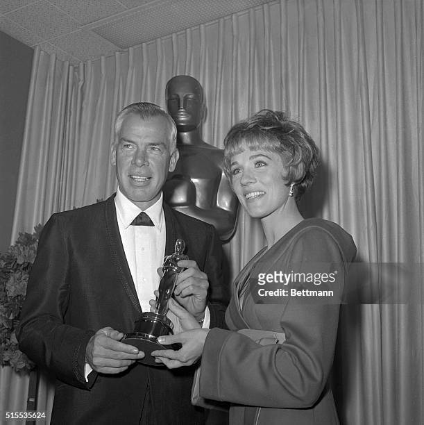 Happy Lee Marvin accepts an Oscar here for "Best Actor of the Year" from lovely Julie Andrews, last year's winner for her role in Mary Poppins....