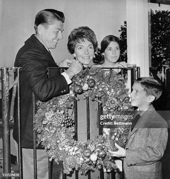 Pacific Palisades, CA.: Governor elect Ronald Reagan, his wife Nancy, daughter Patricia and son Ronald, hang a Christmas wreath at their home 12/22,...