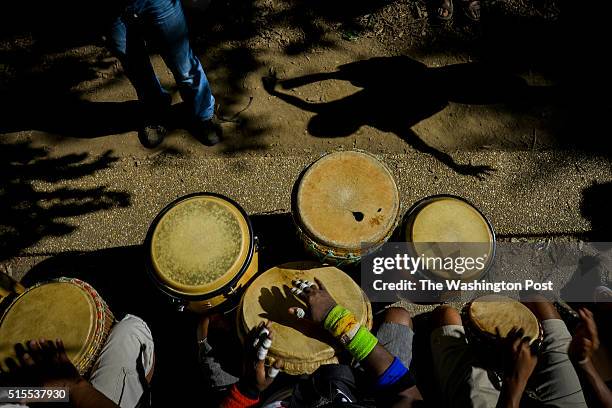 The shadow of Afrika Abney dances to the music of drummers, including Hafez Harris, bottom center, at Meridian Hill Park on Sunday, June 15 in...