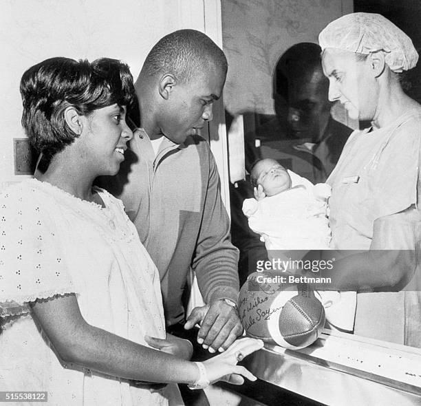 Chicago's Halfback, Gale Sayers, and his wife, Lynn, look at their daughter, Gail Lynne, born at Wesley Memorial Hospital. Holding the 7-pound baby...