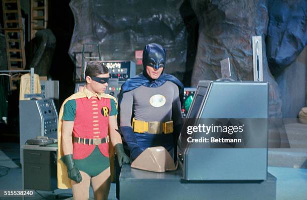 Adam West at "Batman" and Bert Ward as "Robin" stand near the "Batmobile" during filming on an episode from the Batman television series.