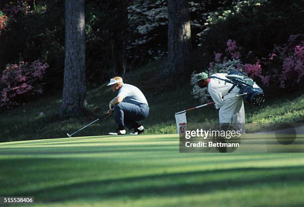 Jack Nicklaus, with caddie at side, lines up birdie for putt at Masters.