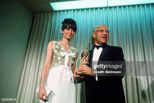 Audrey Hepburn with George Cukor, who accepts an Oscar on behalf of Katharine Hepburn for "Best Performance by an Actress" at the Academy Awards...