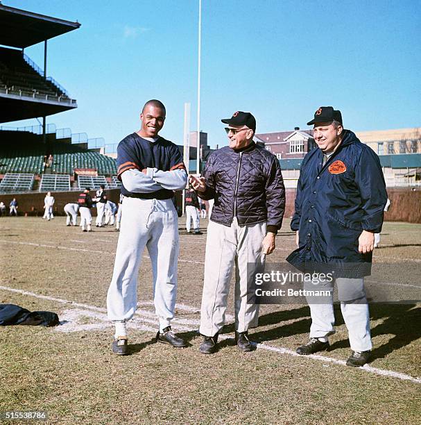 Gale Sayers, Chicago Bears, with coaches George Halas and Abe Gibron on practice field.