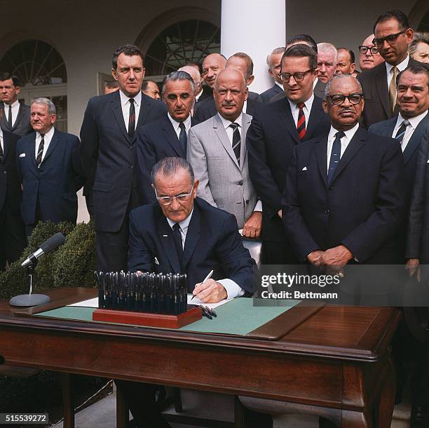 President Lyndon Johnson signs the Civil Rights Act of 1968 into law in a White House ceremony. The tallest man directly behind Johnson is Maine...