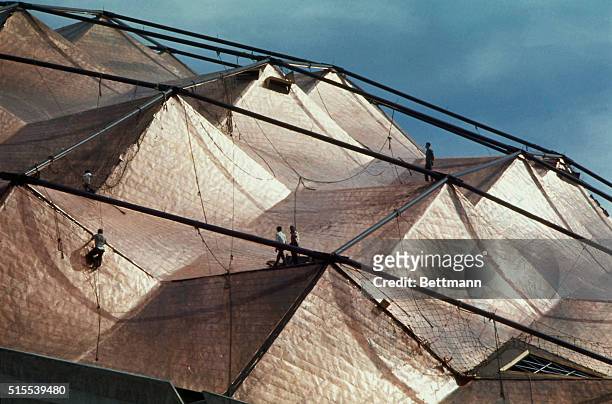 Like spacemen exploring a surrealistic asteroid, workmen clamber over the copper-sheeted Sports Palace dome as it nears completion for the 1968...