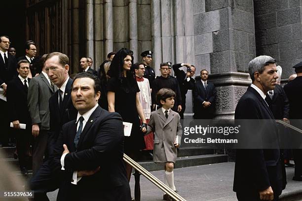 John F. Kennedy Jr., clings to his mother Jacqueline Kennedy, as they leave St. Patrick's Cathedral June 8th following the Requiem Mass for Mrs....