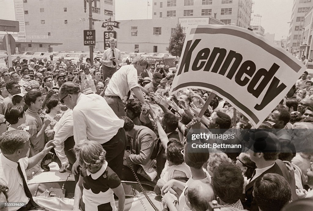 Robert F. Kennedy Shaking Hands Near Large Campaign Signs