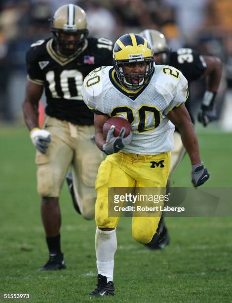 Michael Hart of the University of Michigan Wolverines runs with ball as Ray Edwards and Bobby Iwuchukwu of the Purdue University Boilermakers try to...