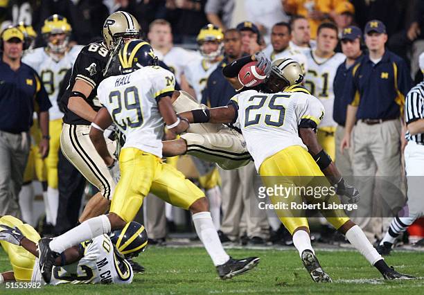 Donen Bryant of the Purdue University Boilermakers looses the ball as he he is tackled by Ernest Shazor of the University of Michigan Wolverines in...