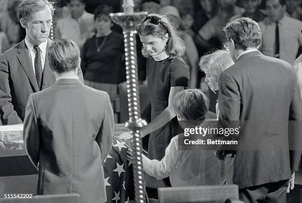 Tenderly placing their hands on the flag-drped casket, Mrs. Jacqueline Kennedy and her children, Caroline and John Jr., pray for Senator Robert F....