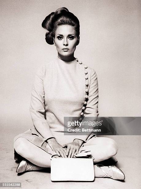 Actress Faye Dunaway wearing a beige broadcloth straitline dress that's buttoned down one side, made for the 1968 film The Thomas Crown Affair by...