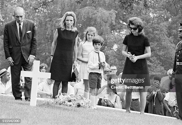 Jacqueline Kennedy and her children, Caroline and John Jr., kneel in prayer at the grave of the late President Kennedy after attending burial rites...