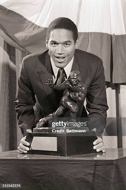 New York, NY- O.J. Simpson, of Southern California, the most celebrated collegiate football player of 1968, looms over the Heisman Memorial Trophy...