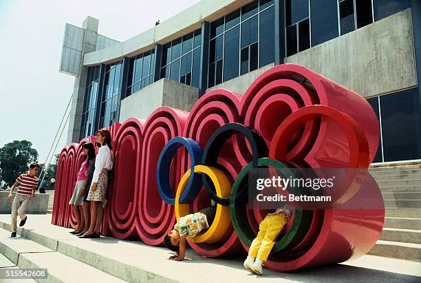 Children play on a big concrete insignia reading "Mexico 68" with the Olympic circles superimposed. Such decor is common in Olympic Village and...