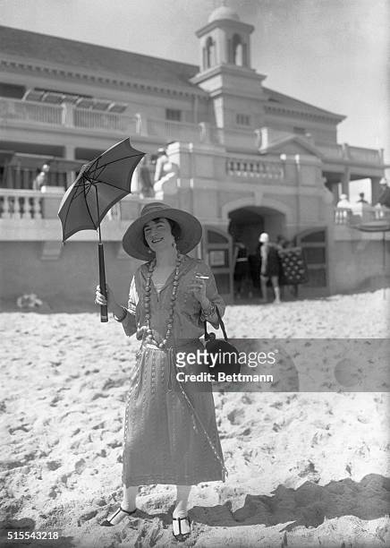 Palm Beach, Fla.: Mrs. Claude Graham White in group on beach, wearing white canary striped stain jersey by Chanel of Paris with hat of canary...