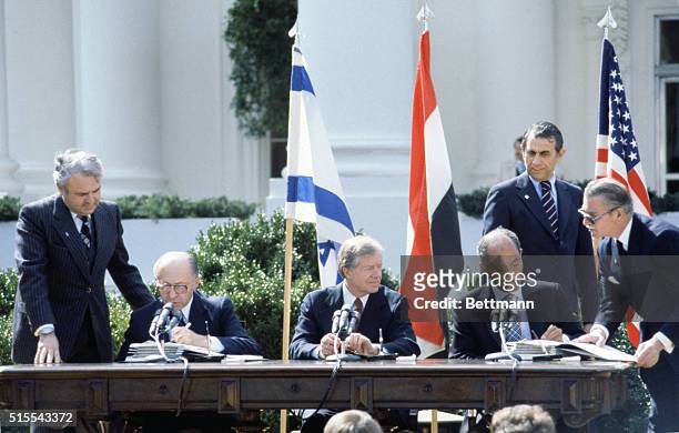 Washington, D.C.: President Carter looks on as Egyptian president Anwar Sadat and Israeli prime minister Menachem Begin put their signatures on the...