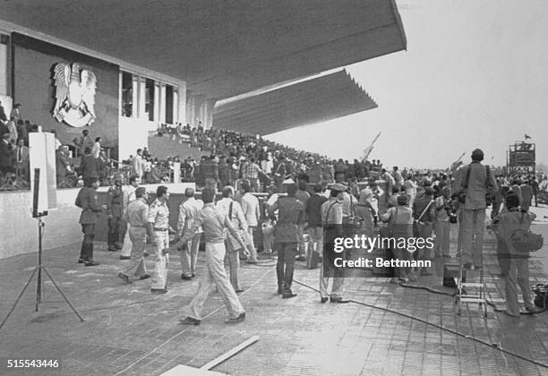 Security police and troops rush to the tarmac where President Anwar Sadat was seated watching the October 6th parade seconds after he was shot and...