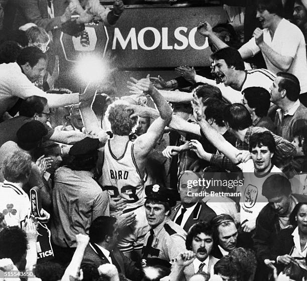 Outstretched arms reach for Celtics' Larry Bird as he leaves the basketball court for the dressing room after the Celtics defeated the 76ers, 91-90,...