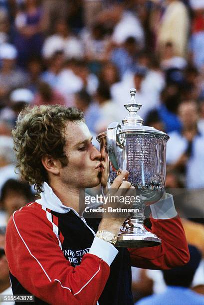 New York, New York: John McEnroe kisses the trophy following his third straight US Open victory, September 13. He defeated Sweden's Bjorn Borg, 4-6,...