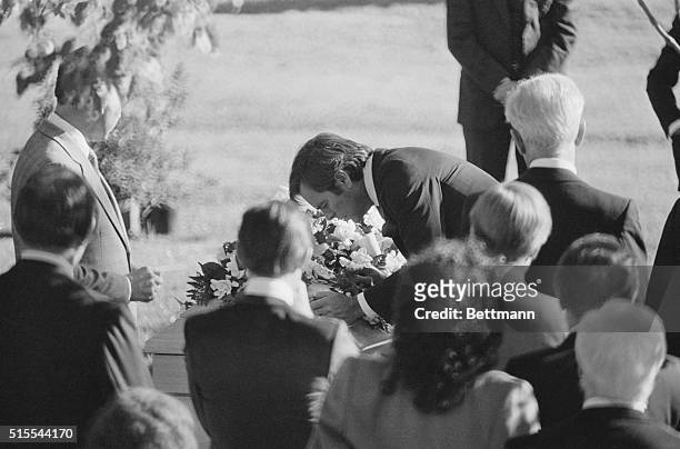 Actor Robert Wagner bends over to kiss flower covered casket of his wife, actress Natalie Wood, during graveside ceremonies for her at Westwood...