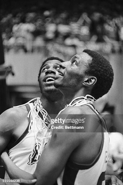Michigan State basketball heroes Earvin Johnson and Gregory Kelser, with pieces of the victory net around their necks, look up at the scoreboard and...