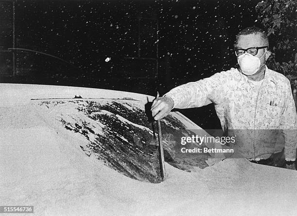 Rick Cole, director of emergency services for Yakima, wears a mask as he uses a snow brush to brush volcanic ash off of his auto's windshield. The...