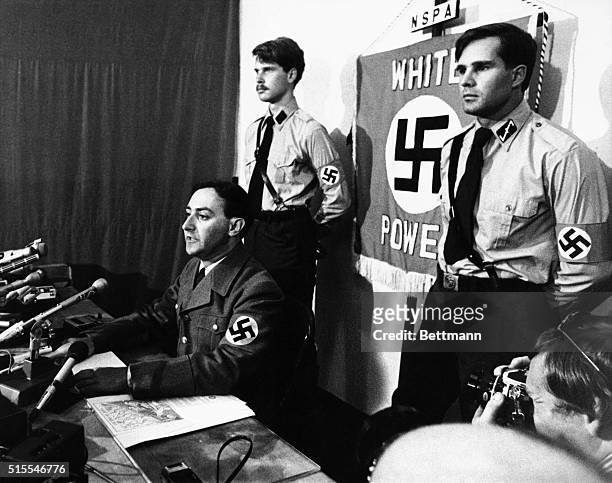 Frank Collin, the leader of the National Socialist Party of America, holds a press conference. Collin, dressed in full Nazi regalia, sits in front of...