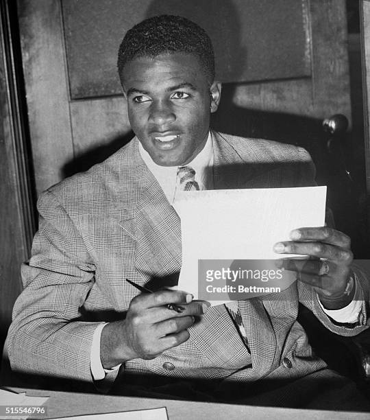 Jackie Robinson holds his contract to play with the Brooklyn Dodgers. Robinson spent 1946 with the Dodgers' minor league team in Montreal, becoming...