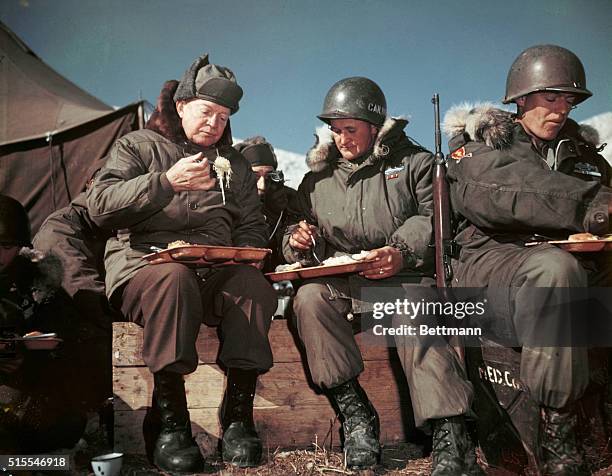 On a visit to the front lines, President Dwight D Eisenhower eats with American soldiers in Korea, December 1952.