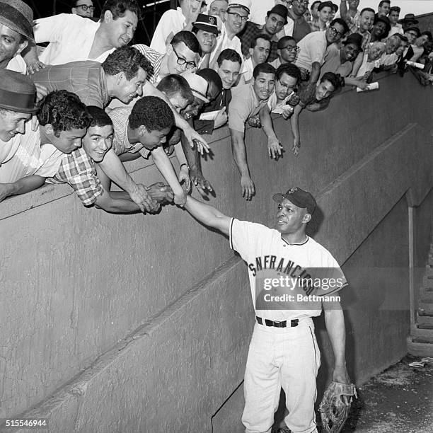 Bleacher fans lean over the wall to greet Willie Mays as he and the San Francisco Giants made their first appearance against the Mets. Willie blooped...