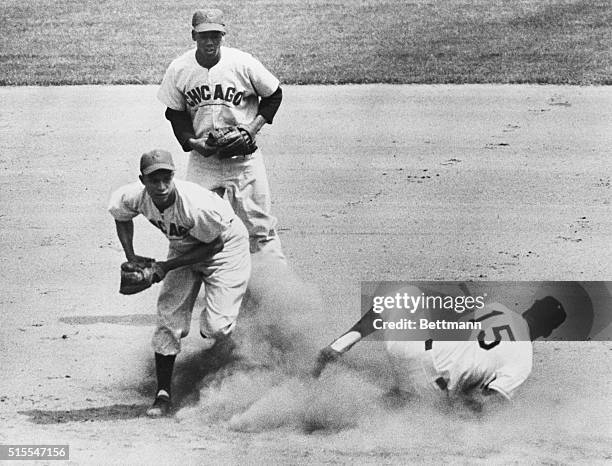 Bill White of the New York Giants creates a cloud of dust as he slides into second base after being tagged out by Chicago Cubs shortstop Ernie Banks...