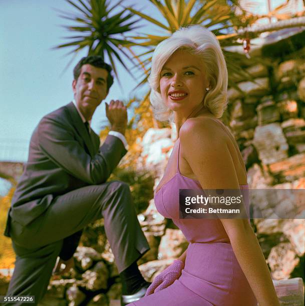Portrait of actress Jayne Mansfield, with an unidentified man posing in the background.
