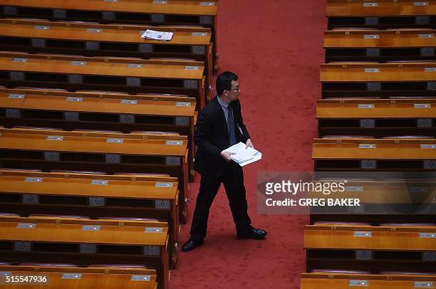 An attendant collects documents from the desks of delegates after the closing session of the Chinese People's Political Consultative Conference at...