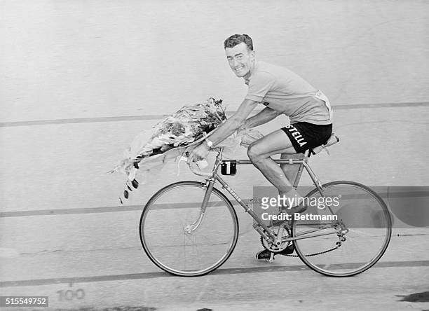 With the victor's bouquet on his handlebars, Louison Bobet, idol of French cycling fans, is riding about the Parc des Princes in Paris after he won...
