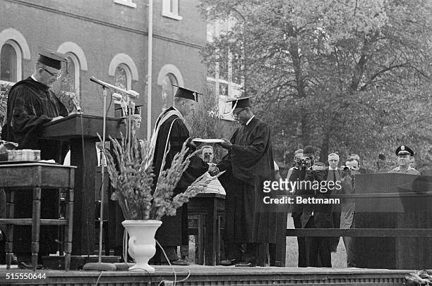 Grinning James Meredith accepts his Bachelor of Arts degree from University of Mississippi Chancellor J. D. Williams here on August 18th. The Negro's...