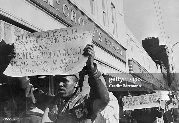 Student carrying a sign walks past McCrory's store here, Feb. 11, as part of a program that will mark one year of protest over segregated eating...