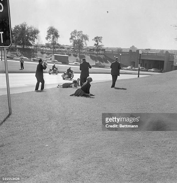 Looking For Cover, Dallas: A newsreel cameraman stands at the left as spectators hug the ground moments after a sniper's bullet ended President...