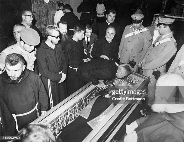 Monk kisses the glass overed coffin of Padre Pio of Pietralcina in the Church of St. Mary of the Graces here. The Capuchin monk considered a Saint by...